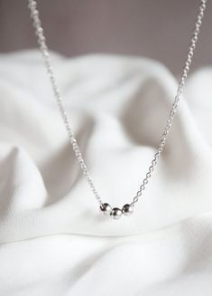 A simple and minimal piece, this tiny bead necklace is sure to become an everyday staple for layering.  3 little satin finish round beads slide freely along delicate chainMATERIALStarnish resistant rhodium silver filled or gold filled charm & chainDIMENSIONS40.6cm (16") plus 2" extender chain, each bead measures 4mm (5/32") diameter◊ Matching sphere jewelry: https://www.etsy.com/shop/kindlingandco/search?search_query=ball◊ More dainty charm necklaces: https://www.etsy.com/shop/kindlingandco? Everyday Sterling Silver Beaded Necklaces, Everyday Minimalist Beaded Necklace With Delicate Chain, Minimalist Everyday Jewelry With Ball Chain, Everyday Minimalist Jewelry With Ball Chain, Everyday Minimalist Ball Chain Jewelry, Minimalist Necklace With Ball Chain And Round Beads, Minimalist Jewelry With Satellite Chain, Minimalist Sterling Silver Necklace With Tiny Beads, Silver Minimalist Beaded Necklace With Delicate Chain