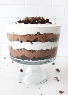 a cake with white frosting and chocolate shavings is on a glass pedestal