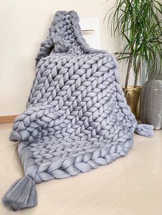 a blue blanket sitting on top of a white floor next to a potted plant