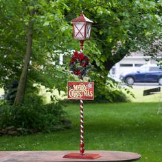 a red and white pole with a christmas sign on it in the middle of a yard