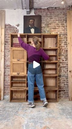 a woman standing in front of a bookcase with an image on the wall behind her