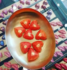 red heart shaped candies on a metal plate in front of pink and purple flowers