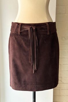 Chocolate brown suede mini skirt with removable fringe belt. Back zip closure. Fits size XS / 0-2 Excellent condition Brown Belted Fitted Mini Skirt, Brown Fitted Belted Mini Skirt, Fitted Brown Belted Mini Skirt, Fitted Brown Mini Skirt With Belt Loops, Brown Belted Mini Skirt, Brown Mini Skirt With Belt Loops, Chic Brown Fringe Skirt, Brown Fringe Mini Skirt, Fringe Belt