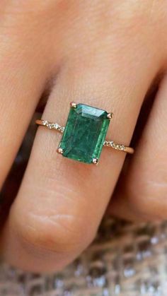 a woman's hand with a ring on her finger and an emerald stone in the middle