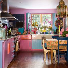 a kitchen with pink and blue walls, wooden floors and colorful furniture in the center