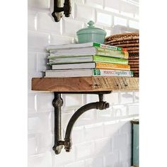 some books are sitting on a shelf with pipe brackets in front of it and a potted plant next to it