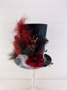 This Halloween steampunk themed top hat is the perfect accent piece for your Halloween decor. It is made with a handmade paper mache hat, paint, glitter, tulle, lace, feathers, fall flower and steampunk gears. The bottom of the brim is made to look like an animal print. This would make a great tree topper or nestled among your holiday decor.  If using as a tree topper, please note the measurements of the top hat to ensure you get an appropriate hat for the size of your tree. Please check the pic High Crown Top Hat For Halloween, Black Steampunk Top Hat For Alternative Fashion, Halloween High Crown Top Hat For Themed Events, High Crown Top Hat For Halloween Themed Events, Steampunk Top Hat With High Crown For Themed Events, Steampunk Costume Accessories For Cosplay, Themed High Crown Top Hat For Halloween, Black Punk Top Hat For Costume Party, Black Punk Style Top Hat For Costume Party