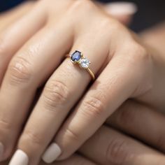 a woman's hand holding an engagement ring with blue and white stones on it