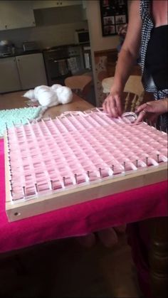 a woman is decorating a cake with pink icing and white frosting on it