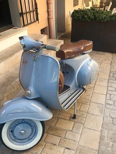 an old blue scooter is parked on the sidewalk