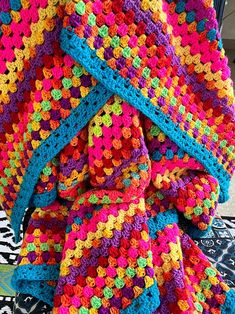 a multicolored crocheted blanket on top of a bed