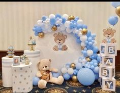 a teddy bear themed baby shower with blue and white balloons on the wall, stuffed animals and decorations