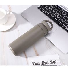 a laptop computer sitting on top of a desk next to a cup and saucer