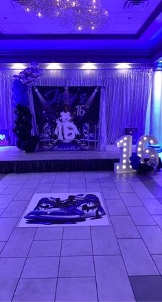 the dance floor is lit up with purple lights and blue draping for decorations