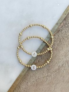 This listing is for ONE beautiful gold filled beaded bracelet with 3mm and 5mm gold filled beads, and a gorgeous shell bead w/gold letter of your choice.  SO beautiful to wear on its own or perfect to layer with your bracelet stack.  Versatile and classic- a treat for yourself or makes the best gift for your loved ones! Please note- the distribution of the 3mm and 5mm beads may be different than pictured, depending on size, but it will look very similar to the samples.   If unsure of sizing, mea Personalized Yellow Gold Beaded Bracelets With Round Beads, Personalized Yellow Gold Beaded Bracelets, Personalized Gold Jewelry With Round Beads, Gold Jewelry With Round Beads For Personalized Gift, Elegant Personalized Gold Beaded Bracelets, Gold Hand-strung Name Bracelet Gift, Personalized Round Bead Gold Bracelets, Dainty Beaded Name Bracelet For Everyday, Personalized Gold Beaded Bracelets As Gift