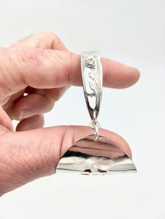 a hand holding a small silver object in it's right hand, with the bottom section