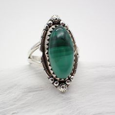 Key Words: Balance | Empathy | Responsibility Zodiac: ♑ Capricorn | ♏Scorpio Chakra: Heart Dimensions: Size 6 | 1.1" long | .5" wide Malachite is a striking green gemstone with unique banding patterns that captivate the eye. Its vibrant green color is often associated with growth, abundance, and transformation. Metaphysically, Malachite is considered a stone of deep healing and emotional balance. It is believed to absorb negative energies, release emotional blockages, and promote positive transf Adjustable Green Onyx Gemstone Jewelry, Green Malachite Cabochon Jewelry, Adjustable Green Turquoise Ring In Spiritual Style, Adjustable Green Turquoise Ring, Spiritual Style, Adjustable Green Jewelry With Large Stone, Spiritual Green Ring With Large Stone, Green Oval Spiritual Jewelry, Spiritual Green Oval Jewelry, Green Jewelry For May Birthstone Collectible