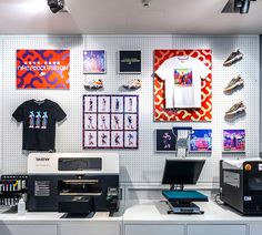 a store display with t - shirts and other items on the wall, including printer equipment