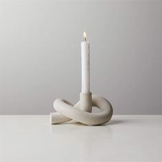 a white candle sitting on top of a table next to an object that looks like a knot