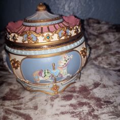 an ornate blue and gold covered box on a patterned tablecloth with pink trimmings