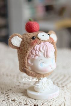 a small doll with a hat on top of it's head and a strawberry on its forehead