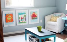 a child's room with blue walls and pictures on the wall, including a coffee table