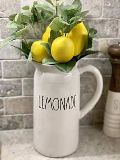 a white pitcher filled with lemons on top of a counter