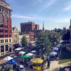 an outdoor market with tents and buildings in the background