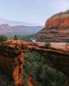 a person standing on the edge of a cliff with their arms spread out in front of them