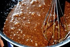 a metal bowl filled with brown liquid and whisks