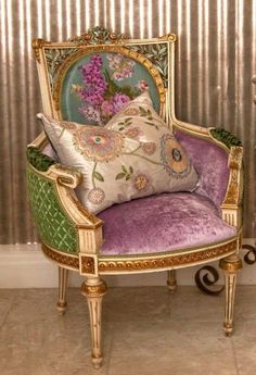 an ornate chair with pillows on it in front of a striped wallpapered room