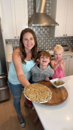 a woman and two children standing in front of a pie