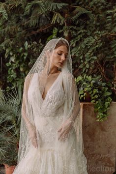 a woman in a wedding dress with a veil over her head and hands on her hips