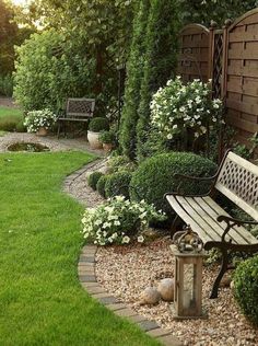 a wooden bench sitting in the middle of a lush green yard next to a stone path