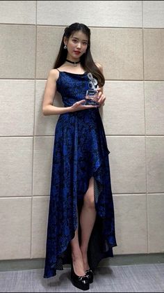 a woman standing in front of a wall holding an award