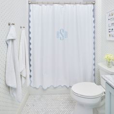 a monogrammed shower curtain in a bathroom with white and blue decor on the walls