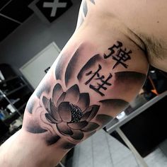 a man's arm with a lotus tattoo on it and chinese characters in the background