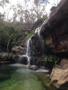 there is a small waterfall in the middle of some rocks and green water below it