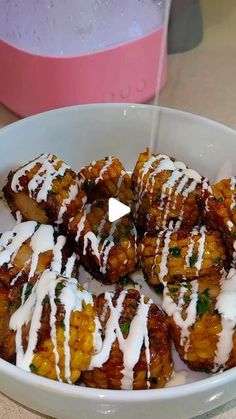 a bowl filled with fried food covered in white sauce and drizzled on top