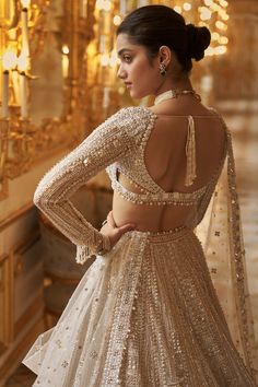 This lehenga set features delicate embroidery in ivory and gold sequin in a geometric pattern,. The full sleeves blouse has a plunging neckline and shows pearl and crystal tassels at the waist and wrist. It is paired with a matching four sided embroidered dupatta.From Seema Gujral's Inara collection. DELIVERY TIMEPlease allow 8-12 weeks for your outfit to arrive. FABRIC DETAILSNet Professional cleaning only. Sequin Lehenga, Seema Gujral, Gold Lehenga, Pengantin India, Full Sleeve Blouse, Pearl Embroidery, Embroidered Belt, Indian Dresses Traditional, White Gown