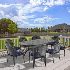 an outdoor dining table and chairs on a deck with white picket fence in the background