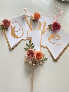 a cake topper with flowers on it and the letter e is made out of paper