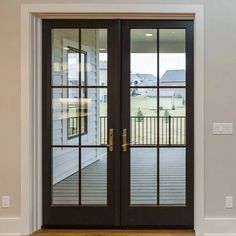 two double doors with glass on each side in front of a white wall and wooden floor