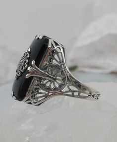 Black Glass/Stone & CZ Ring Grace Design#233 Custom Made I now offer this lovely Antique Art Deco/Edwardian design ring in sterling silver. This gorgeous ring is set with a stunning floral filigree embellished black glass/resin with a centered set 1mm white CZ. The Black glass is 18mm Long by 19mm Wide. The ring sits 19mm NS in the finger and 10mm EW on the finger. The inside of the band is marked 925 for sterling. Notice the beautiful leaf geometric design of the filigree band and setting. Luxury Onyx Jewelry For Weddings, Classic Formal Gemstones With Stone Setting, Elegant Black Rings With Gemstone Accents, Art Deco Evening Gemstone Jewelry, Elegant Onyx Rings Hallmarked, Elegant Hallmarked Onyx Rings, Classic Onyx Jewelry For Wedding, Formal Onyx Gemstone Rings, Classic Sterling Silver Rings With Gemstone Accents