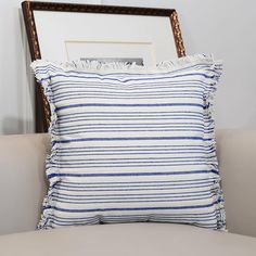 a blue and white striped pillow sitting on top of a couch next to a framed photograph