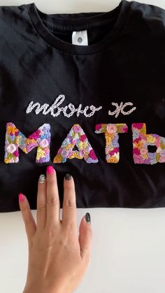 a woman's hand is holding onto the letters that spell out math on a black t - shirt