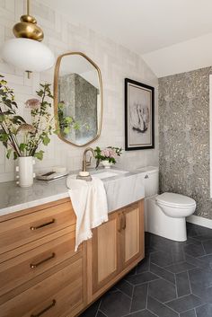 a bathroom with a marble counter top and wooden cabinetry next to a white toilet