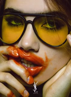 a woman with orange paint on her face and eyeglasses is posing for the camera