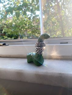 a green sculpture sitting on top of a window sill