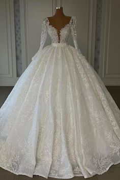 a white wedding dress with long sleeves and lace on the skirt is displayed in front of a